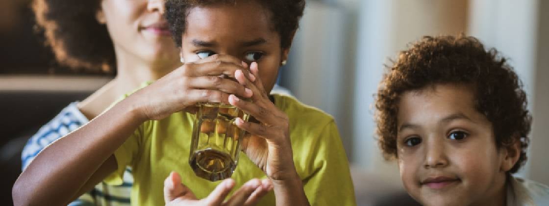 Una niña tomando agua después de practicar ejercicios de comprensión lectora para niños