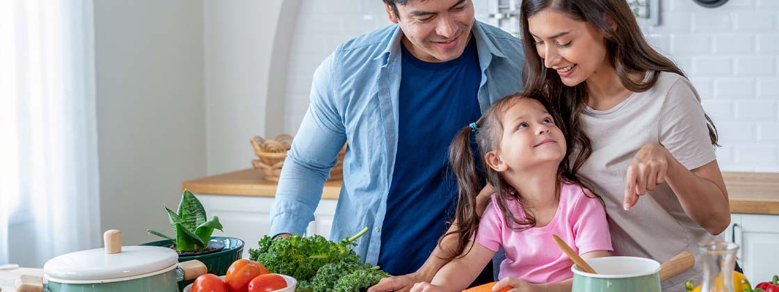 Papás e hija preparando una comida para la cena temática mientras tienen buena comunicación familiar