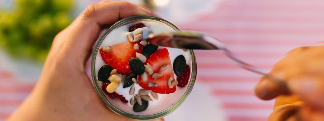 Una persona comiendo un desayuno creativo para niños con yogurt y frutas